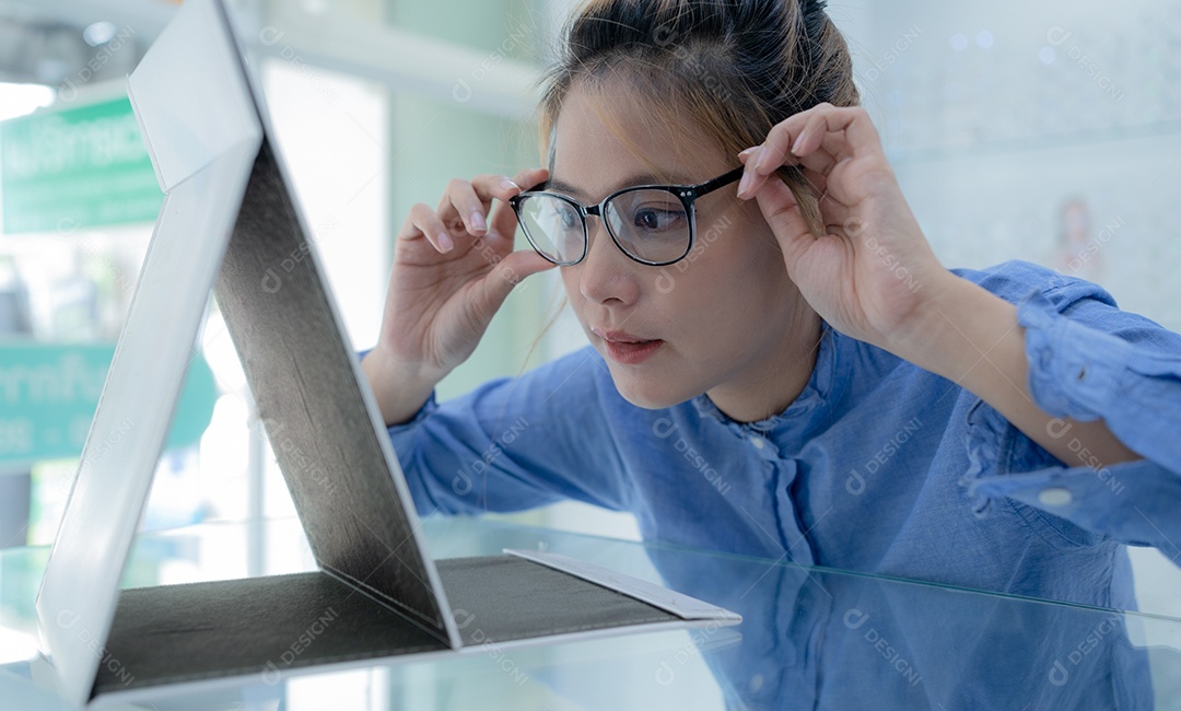 A garota experimentou os óculos e se olhou no espelho.