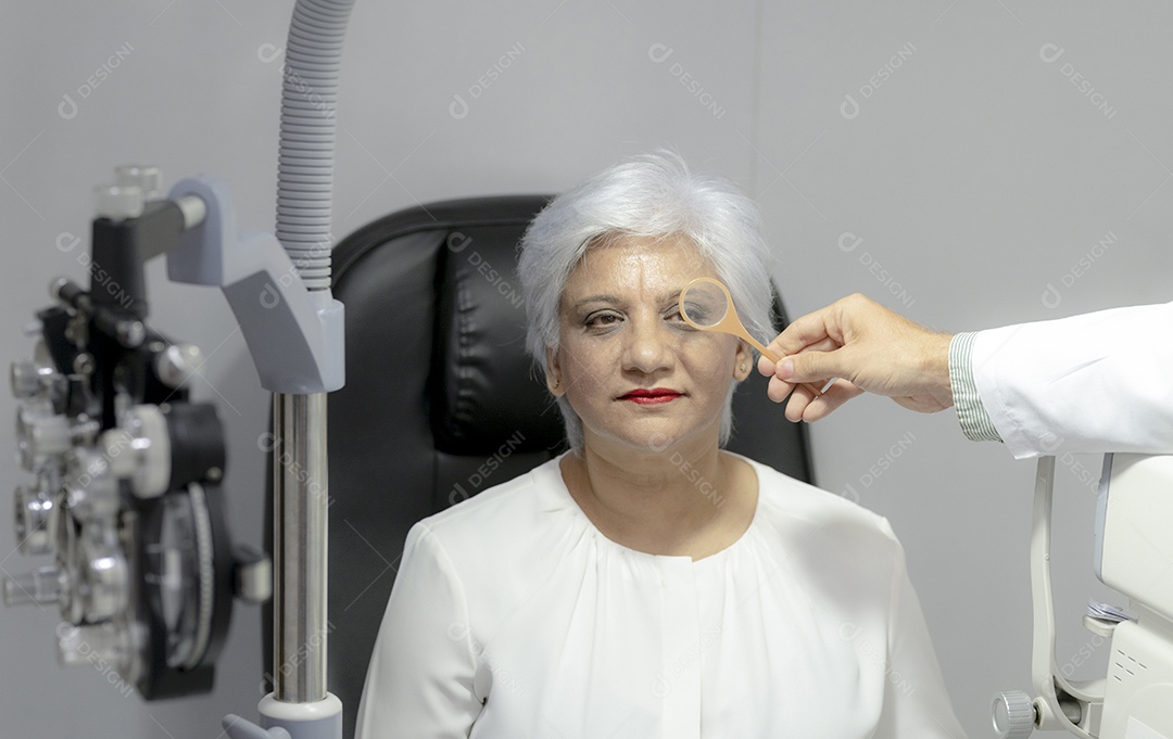 Mulher idosa têm seus olhos examinados por um oftalmologista.