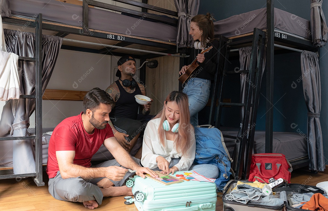 Grupos de viajantes de várias nacionalidades se reúnem em um albergue, selfies para guardar memórias, homem engraçado usando smartphone na cama superior, mochileiros.