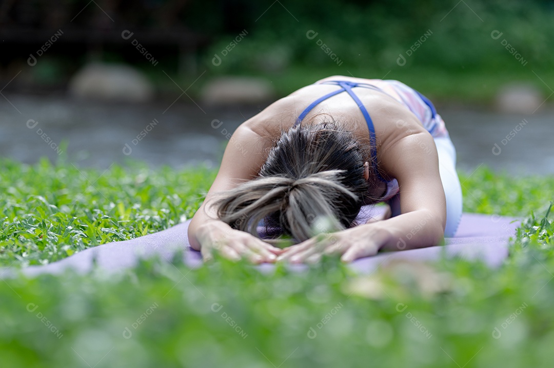 Jovem mulher fazendo exercícios de ioga ao ar livre.