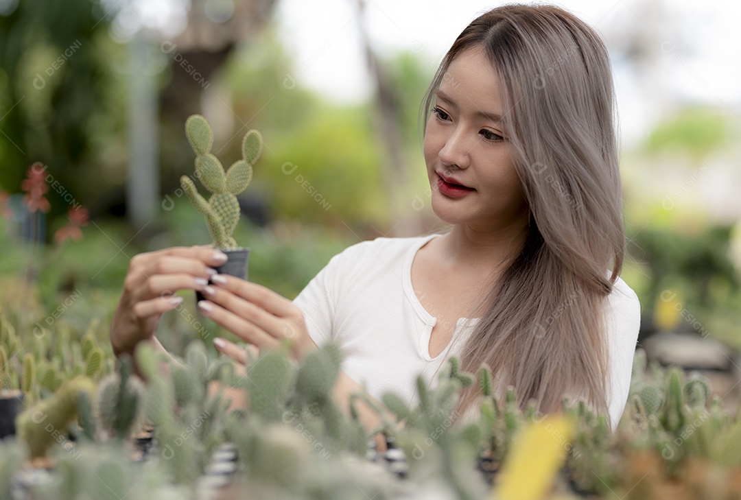 Mulher asiática sorridente segurando tesouras de poda de plantas em vasos, vasos de plantas pretos pendurados no jardim, cuidando de plantas de jardim para venda, beleza e natureza.