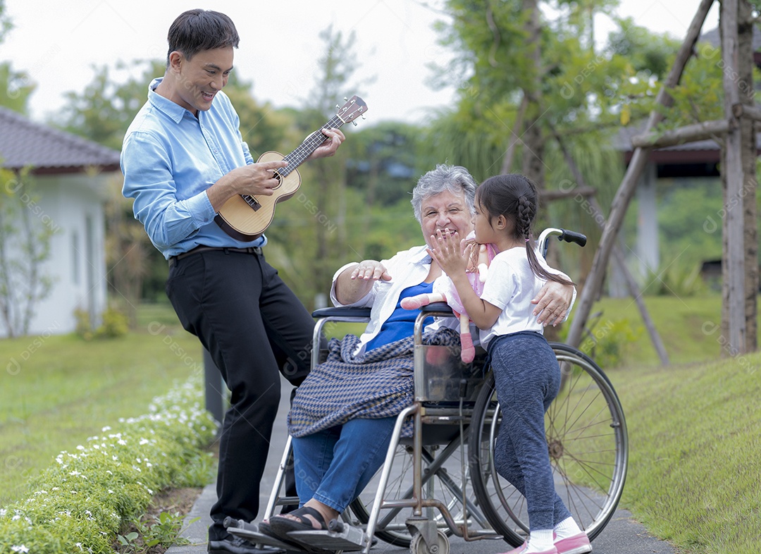 Jovem asiático e garota tocando ukulele e cantando com uma mulher idosa em uma cadeira de rodas em um lar de idosos, relaxamento de idosos, cuidados de enfermagem.