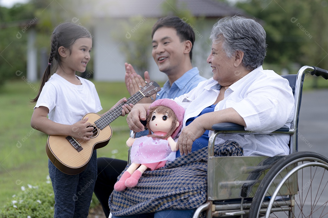 Jovem asiático e garota tocando ukulele e cantando com uma mulher idosa em uma cadeira de rodas em um lar de idosos, relaxamento de idosos, cuidados de enfermagem.