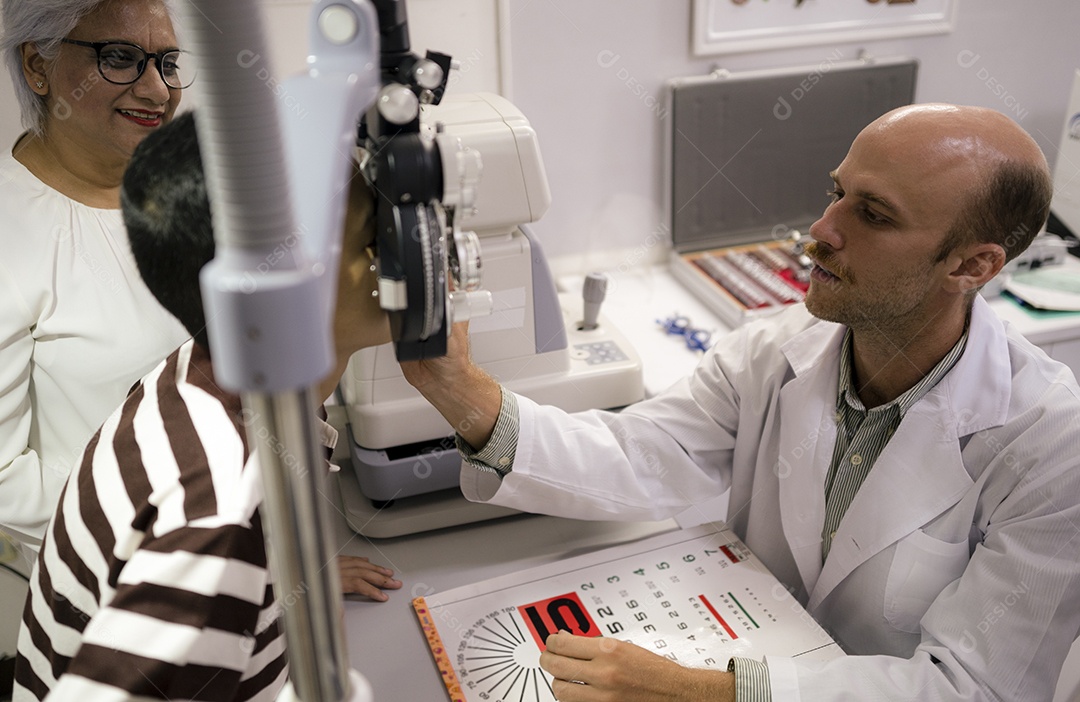 Oftalmologista asiática examinando os olhos do menino com equipamento especial com a avó ao lado, especialista em oftalmologia, saúde ocular.