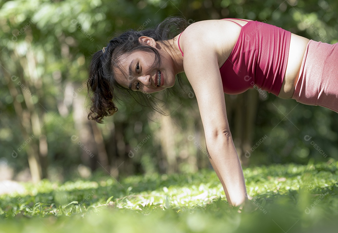 Mulher asiática fazendo poses de ioga para relaxamento, ioga para meditação, exercícios no gramado ao ar livre.