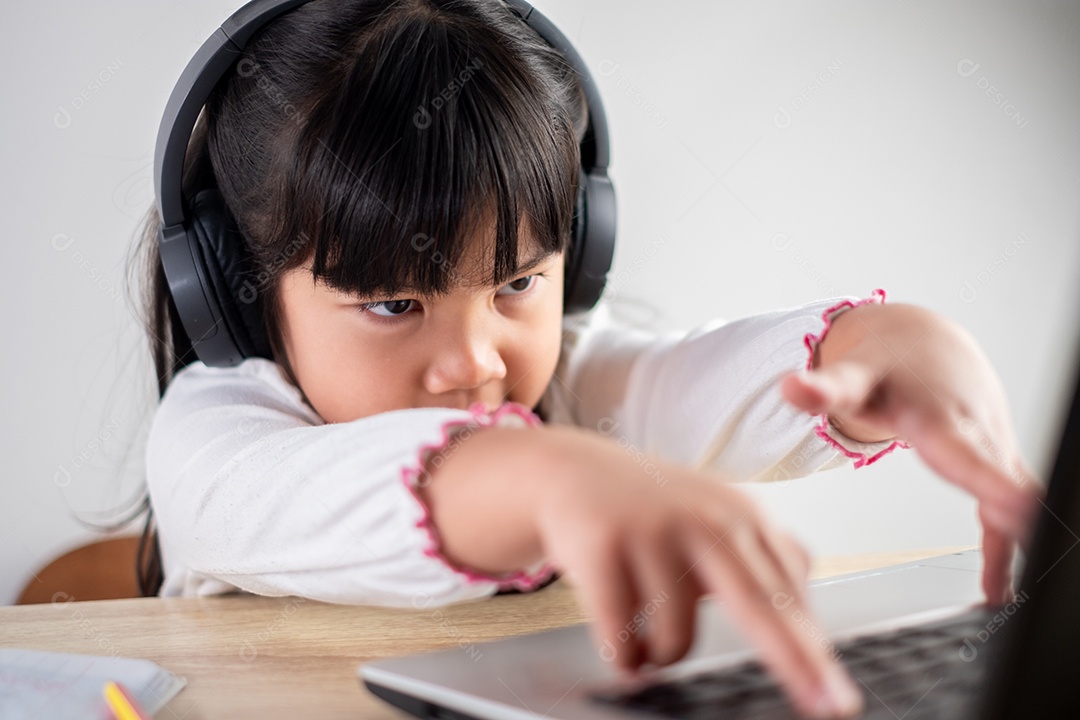 Menina asiática de 4-5 anos vestindo camisa branca está estudando online
