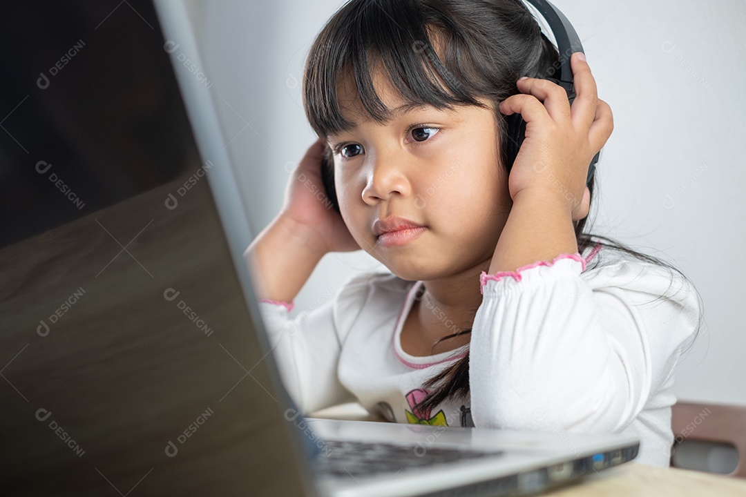 Menina asiática de 4-5 anos vestindo camisa branca está estudando online
