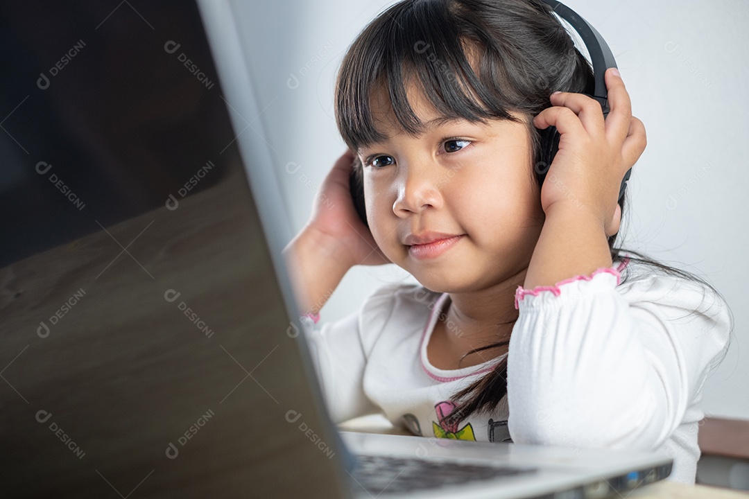 Menina asiática de 4-5 anos vestindo camisa branca está estudando online