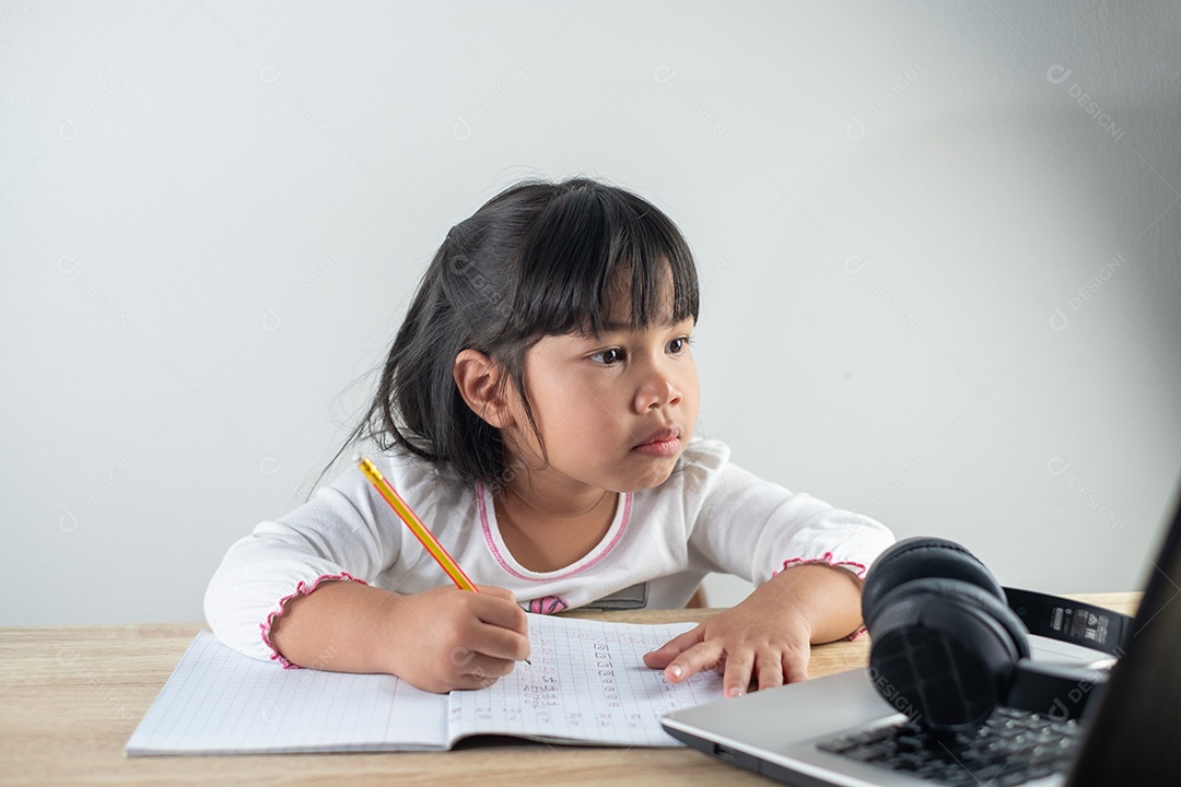 Menina asiática de 4-5 anos vestindo camisa branca está estudando online