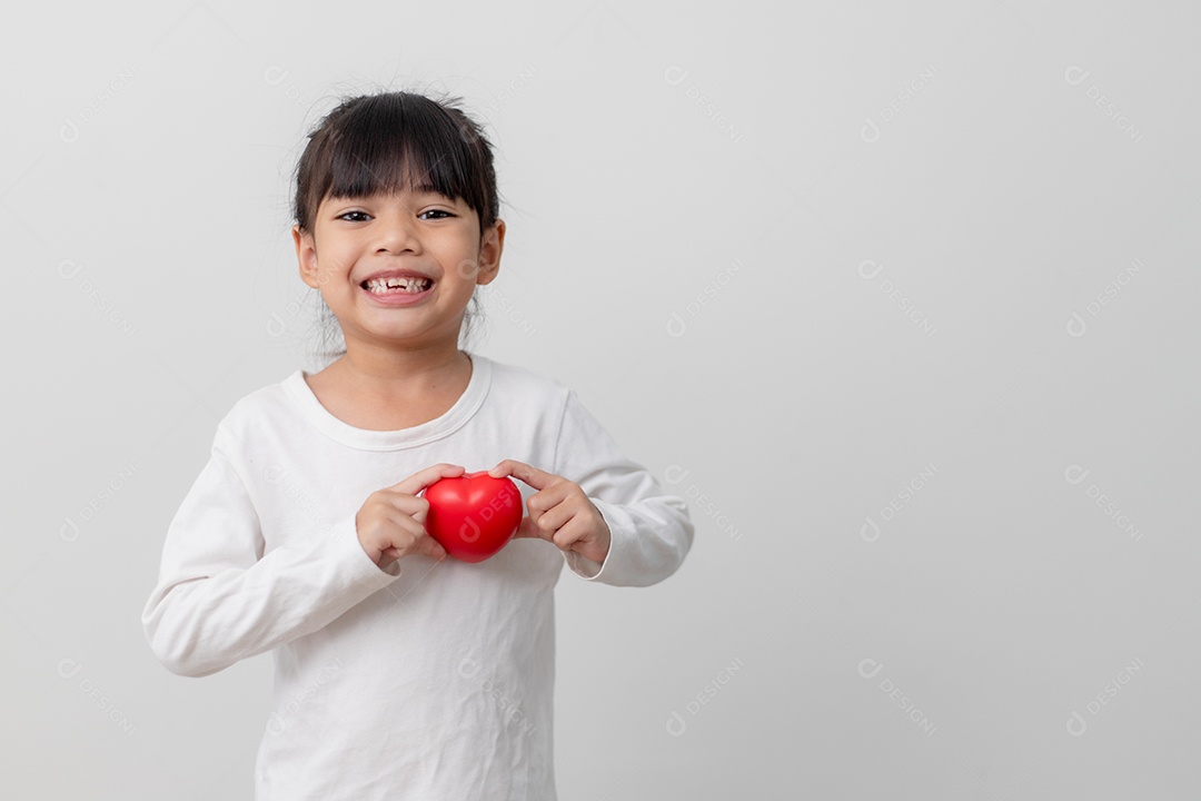 Retrato de uma garotinha asiática segurando uma placa de coração vermelho.