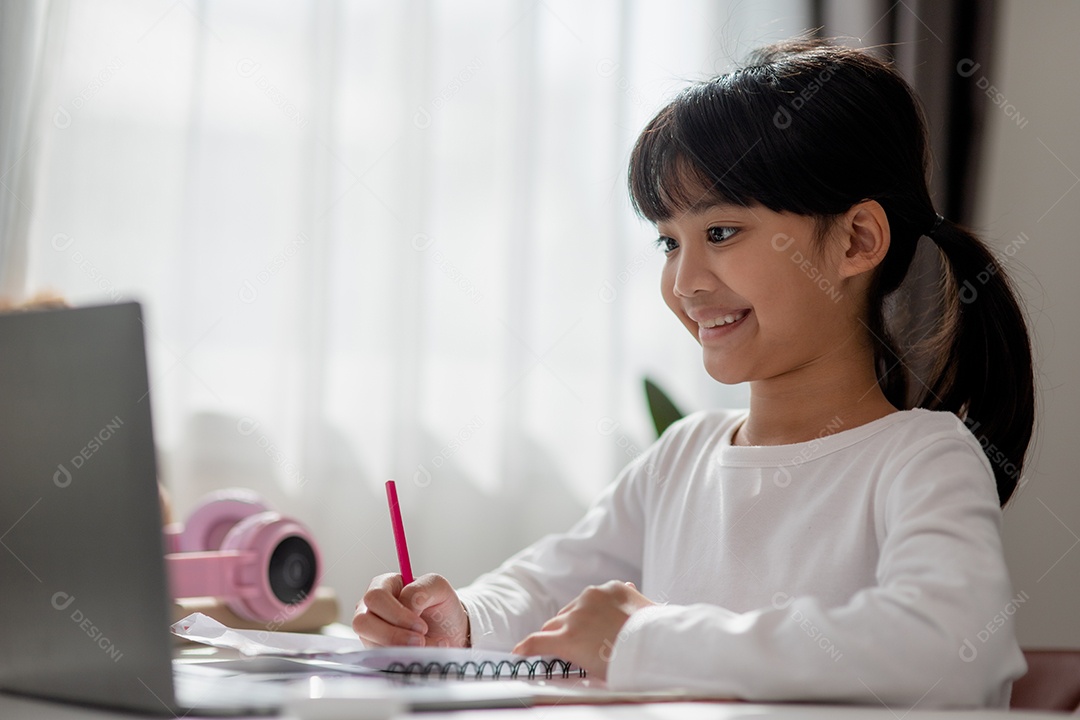 Aluna asiática fazendo sua lição de casa com o laptop em casa.