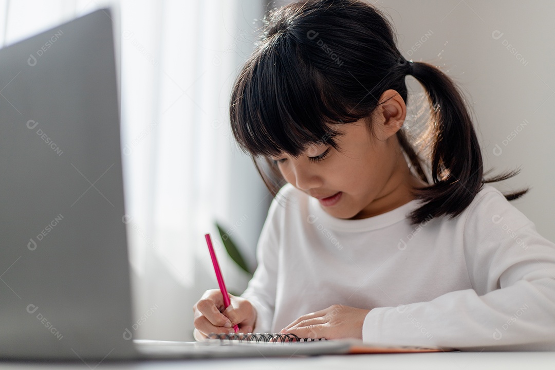 Aluna asiática fazendo sua lição de casa com o laptop em casa.