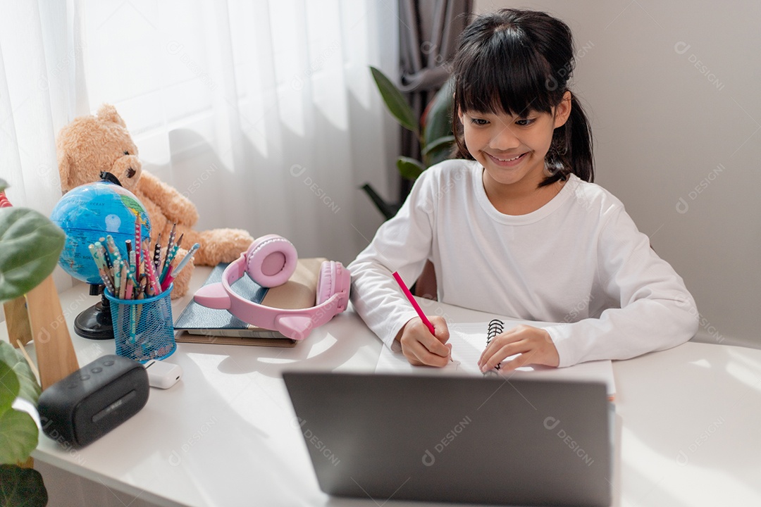 Aluna asiática fazendo sua lição de casa com o laptop em casa.