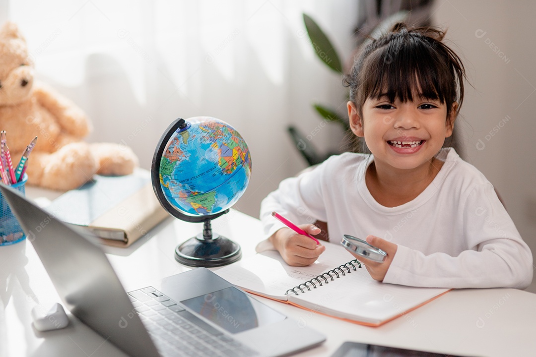 Aluna asiática fazendo sua lição de casa com o laptop em casa.