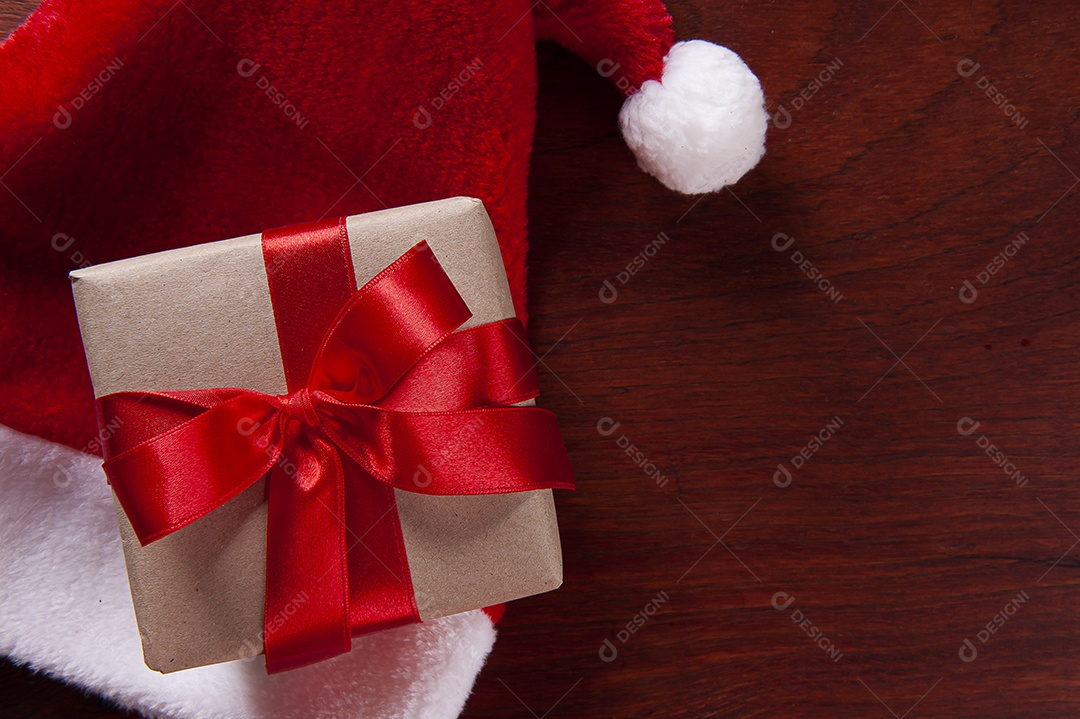 Composição de natal com presente e chapéu de Papai Noel em fundo de madeira