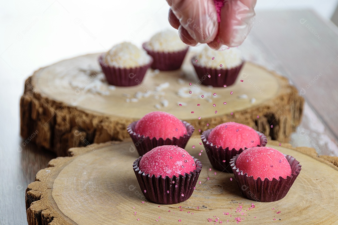 Brigadeiro de morango cercado por brigadeiros tradicionais