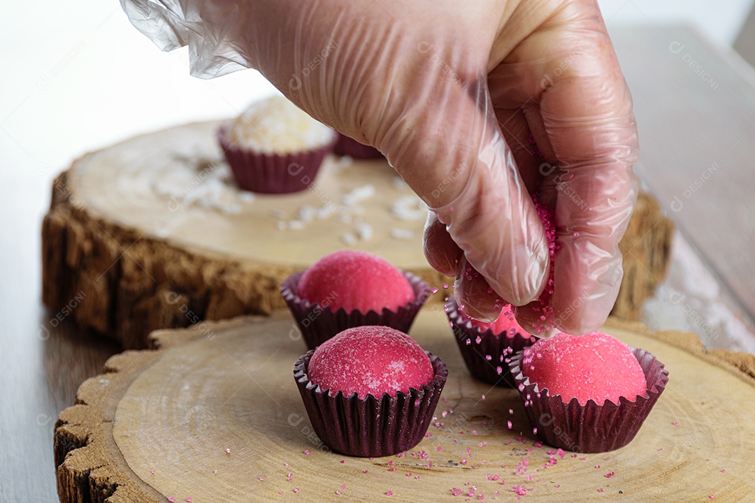 Brigadeiro de morango cercado por brigadeiros tradicionais