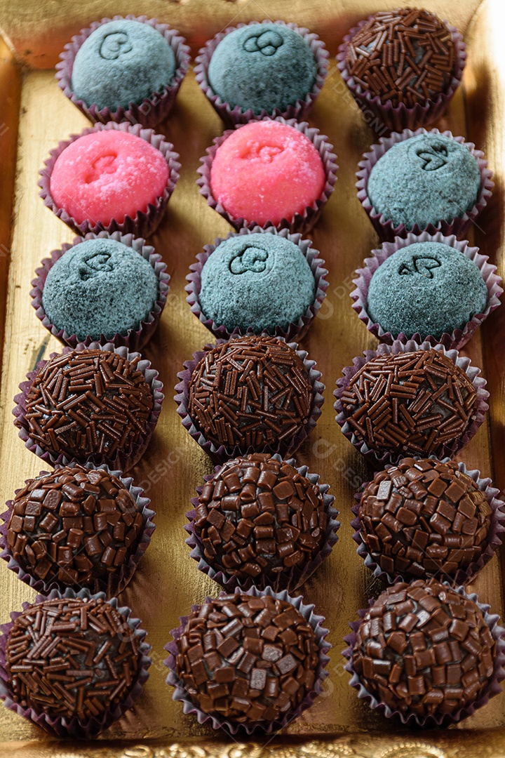 Detalhe de brigadeiro de morango cercado por brigadeiros tradicionais