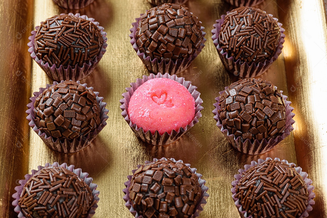 Detalhe de brigadeiro de morango cercado por brigadeiros tradicionais