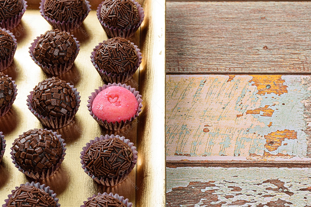 Brigadeiro de morango cercado por brigadeiros tradicionais