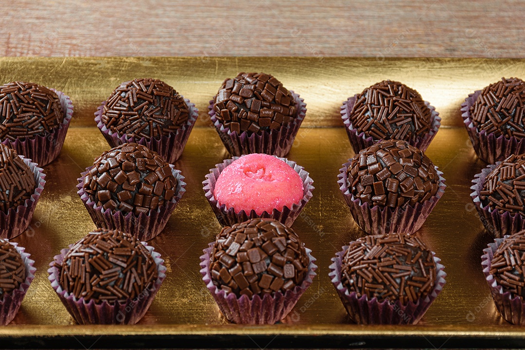 Brigadeiro de morango cercado por brigadeiros tradicionais