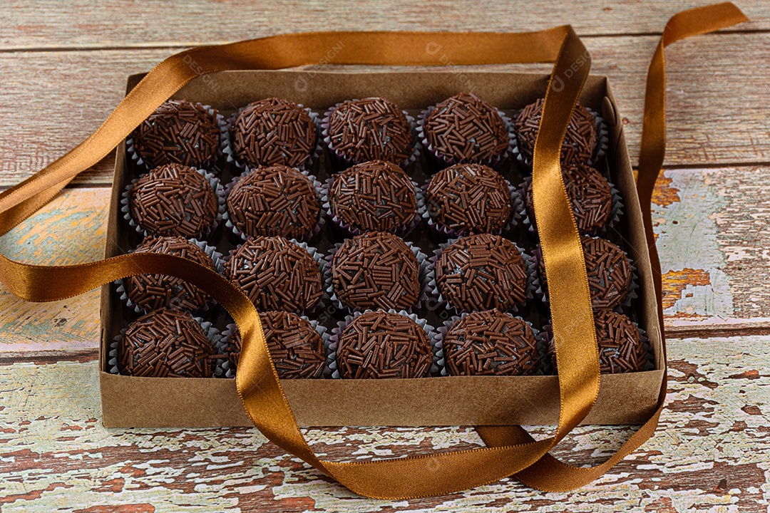 Detalhe de brigadeiro de morango cercado por brigadeiros tradicionais