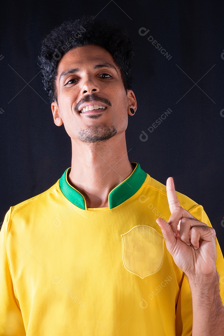 Jogador negro de futebol brasileiro comemorando, isolado em fundo preto.