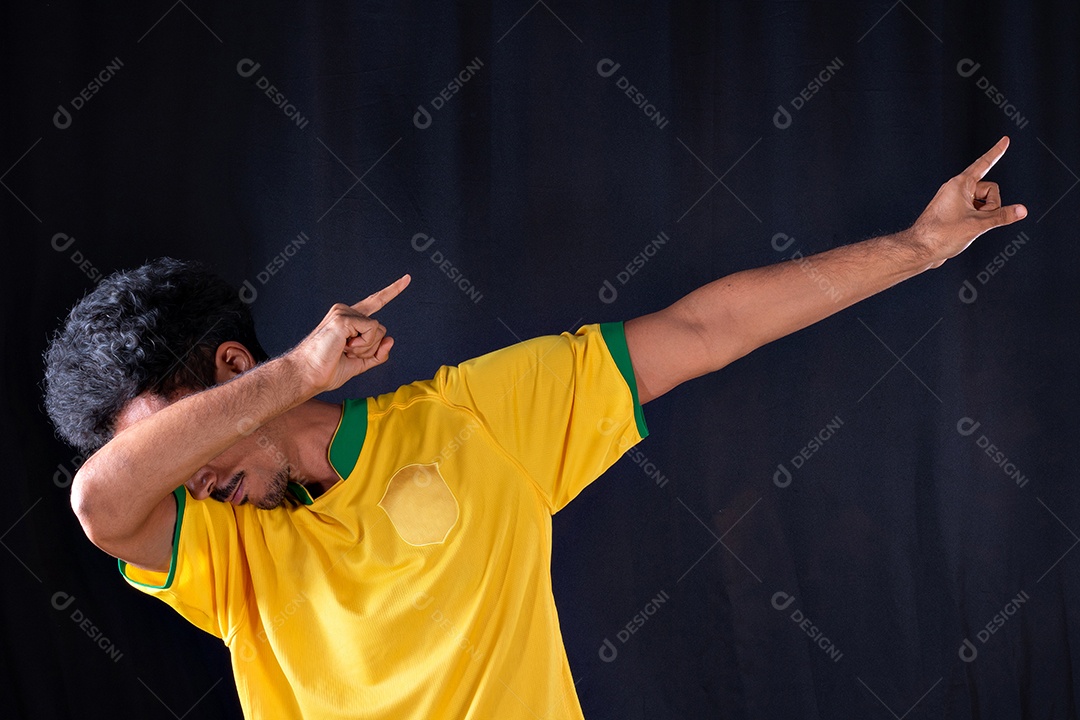 Jogador negro de futebol brasileiro comemorando, isolado em fundo preto.