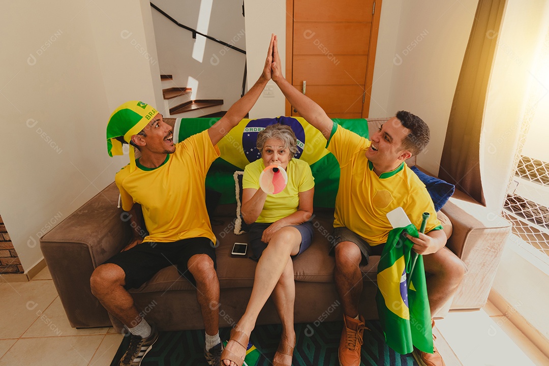 Família mestiça brasileira Comemorando a copa na sala assistindo jogo de futebol.