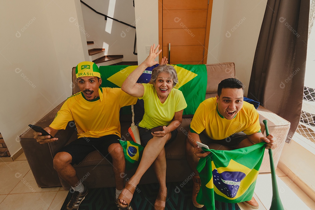 Família mestiça brasileira Comemorando a copa na sala assistindo jogo de futebol.