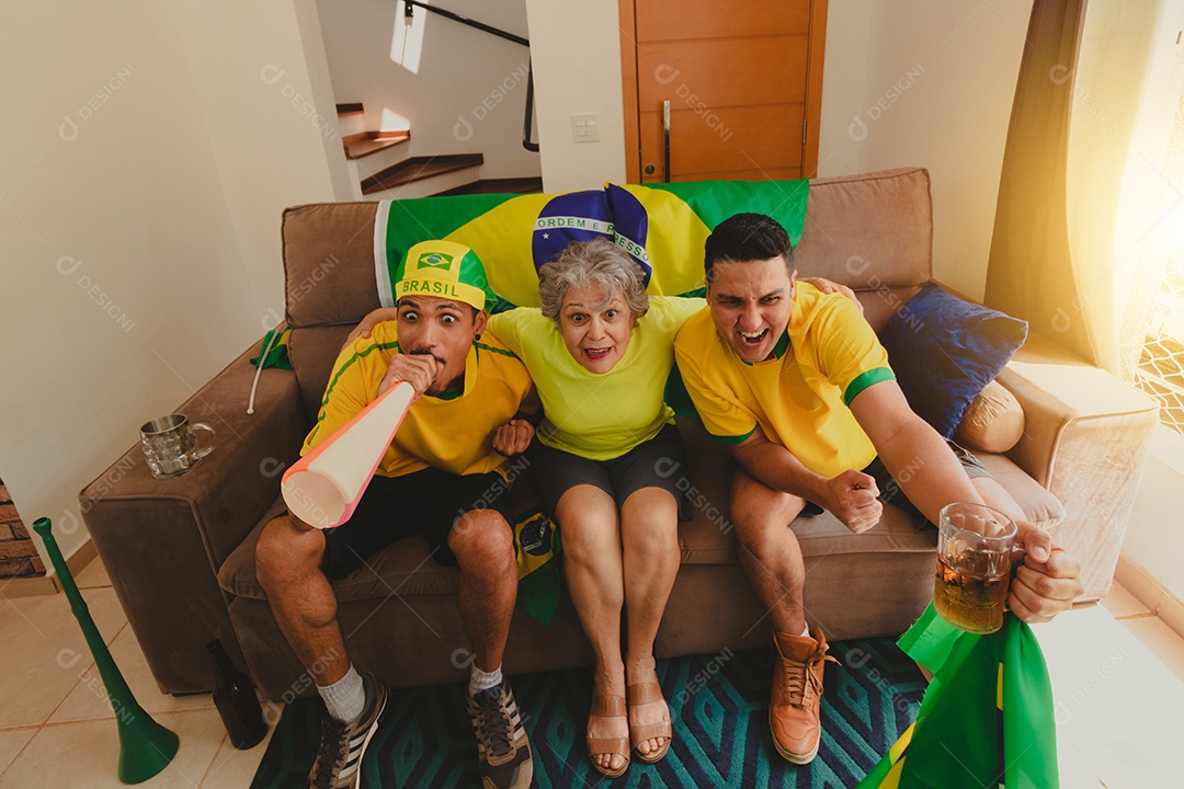 Família mestiça brasileira Comemorando a copa na sala assistindo jogo de futebol.