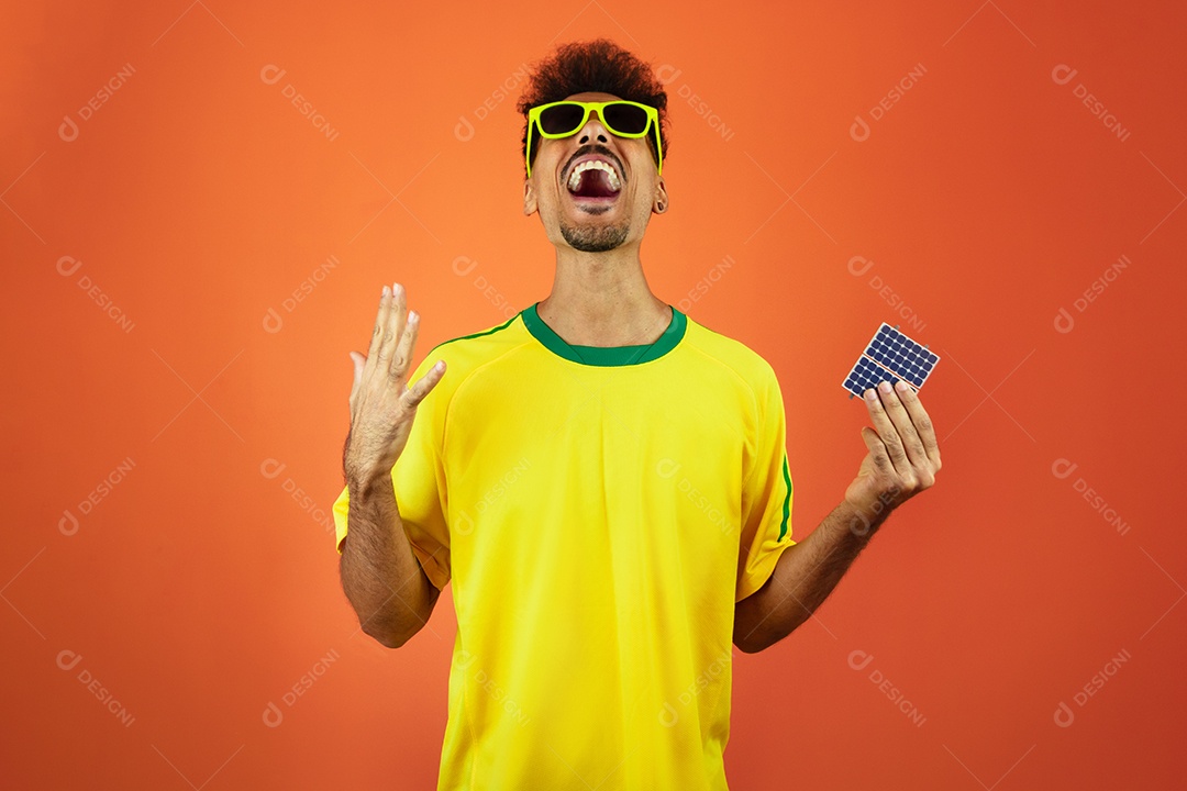Jogador de futebol - homem negro comemorando segurando painel solar fotovoltaico isolado em laranja