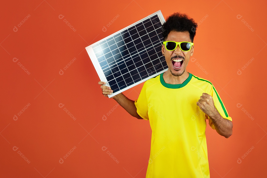 Jogador de futebol - homem negro comemorando segurando painel solar fotovoltaico isolado em laranja