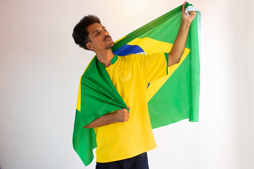 Fã de homem negro brasileiro com camisa de time de futebol isolado no branco. Fã do esporte com bandeira comemorando a Copa.