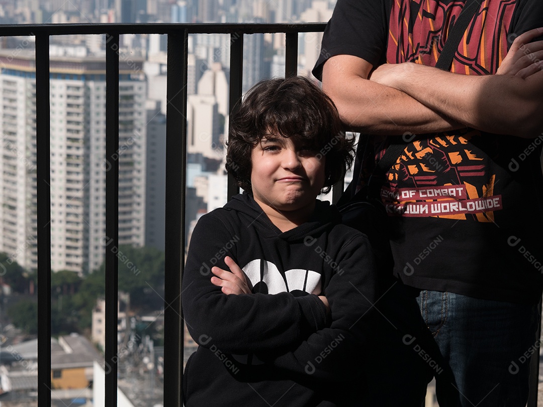 Pai e filho posando para a câmera em cima de um prédio no centro de São Paulo.