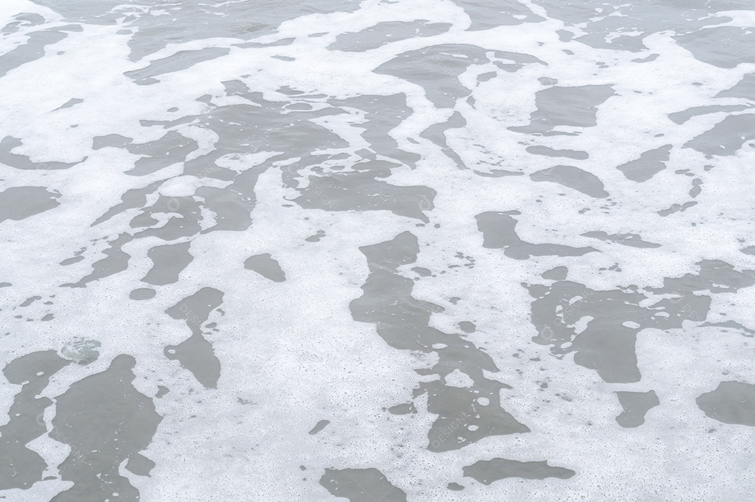 Superfície de praia de areia cinza ou escura com forma estranha de espuma