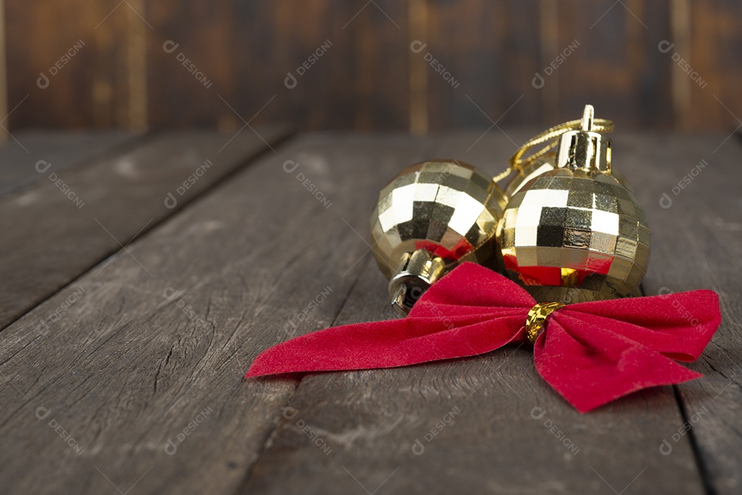 Bolas de natal douradas e laço vermelho de presente sobre a mesa de madeira