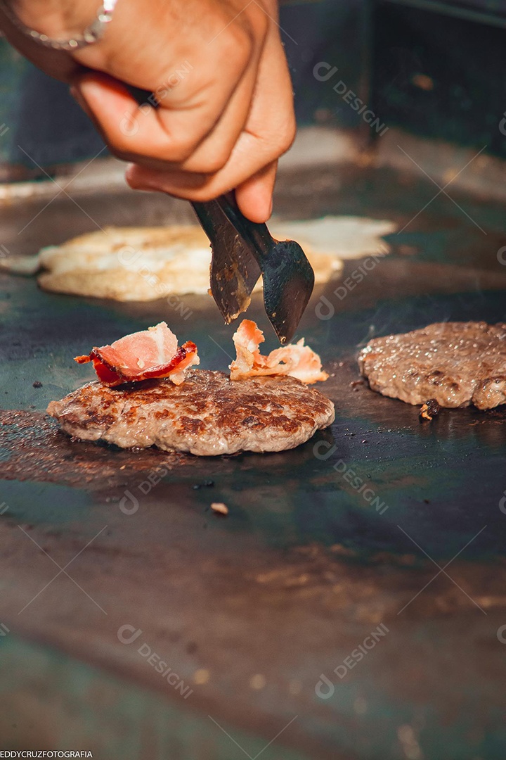 Carnes para hamburgueres e ovos sendo fritados na chapa.