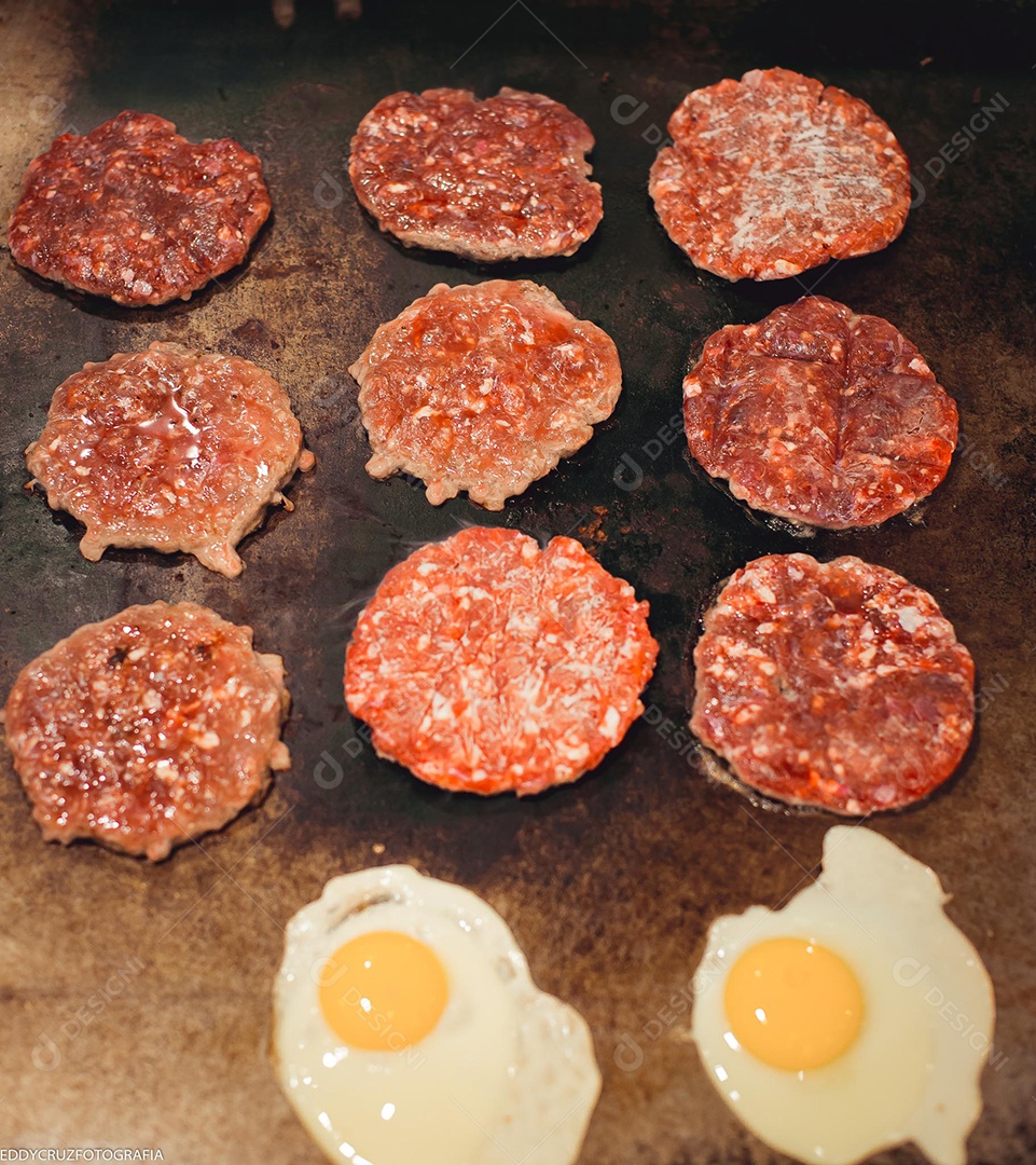 Carnes para hamburgueres e ovos sendo fritados na chapa.