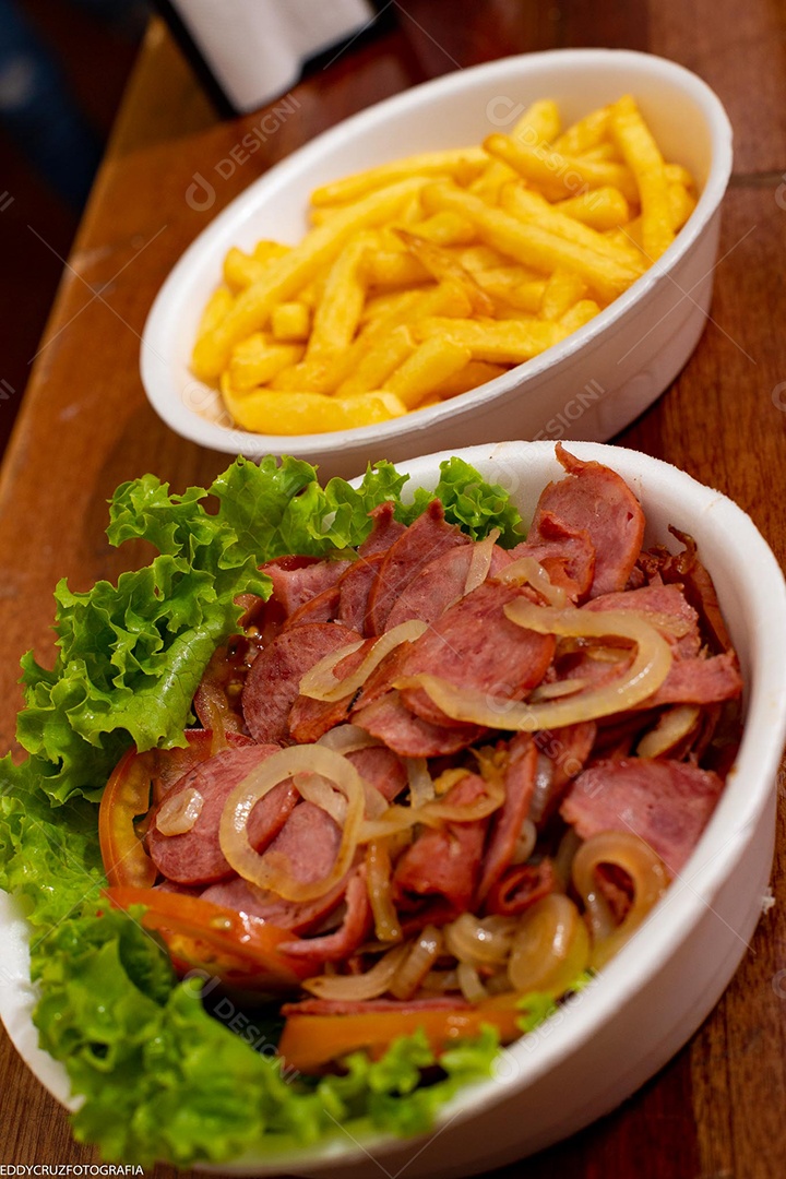 Porções de calabresa acebolada com batatas fritas, servidos em marmitex de isopor.