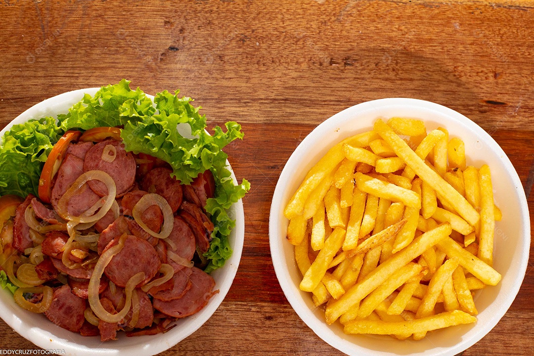 Porções de calabresa acebolada com batatas fritas, servidos em marmitex de isopor.