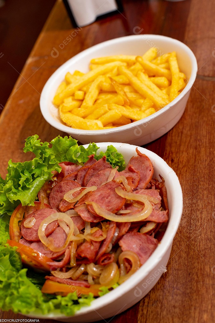 Porções de calabresa acebolada com batatas fritas, servidos em marmitex de isopor.