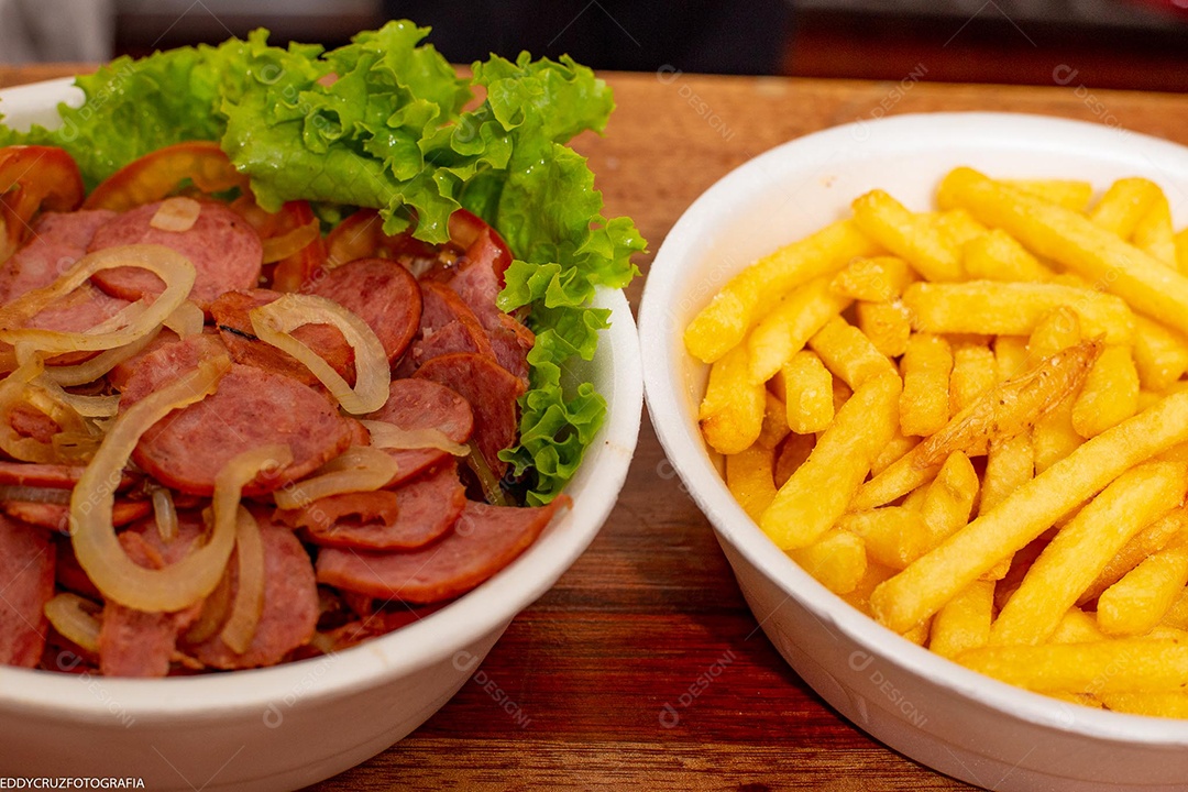 Porções de calabresa acebolada com batatas fritas, servidos em marmitex de isopor.