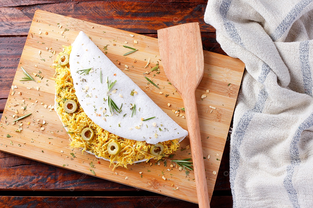 tapioca caseira ou beiju recheado com frango cozido e azeitonas na mesa de madeira rústica. vista do topo
