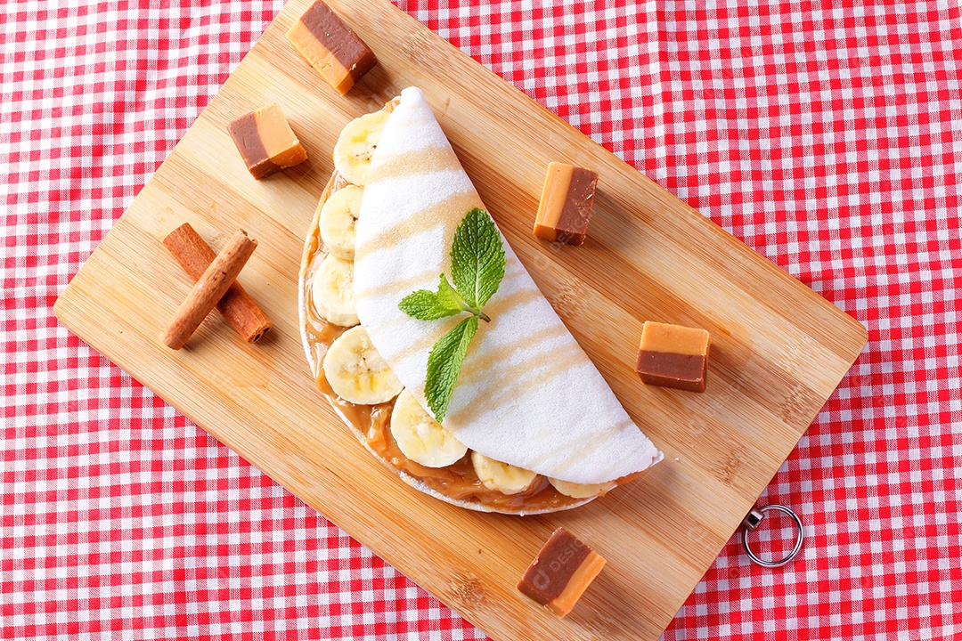 tapioca caseira ou beiju recheado com banana e leite condensado ou caramelo maltado na mesa de madeira rústica. vista do topo