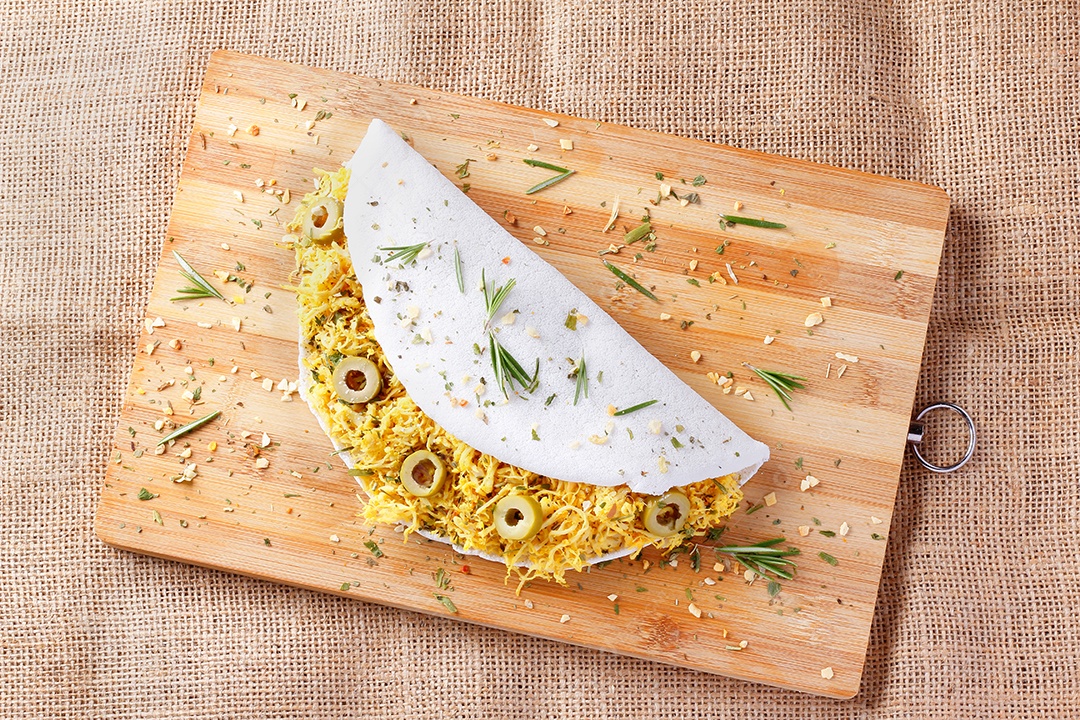 tapioca caseira ou beiju recheado com frango cozido e azeitonas na mesa de madeira rústica. vista do topo