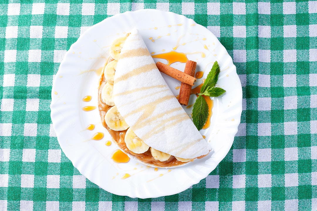 tapioca caseira ou beiju recheado com banana e leite condensado ou caramelo maltado na mesa de madeira rústica. vista do topo