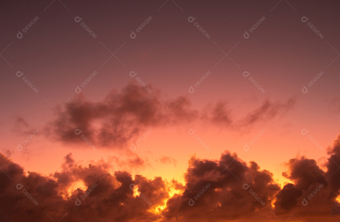 Vista do nascer do sol com nuvens dramáticas e céu colorido.