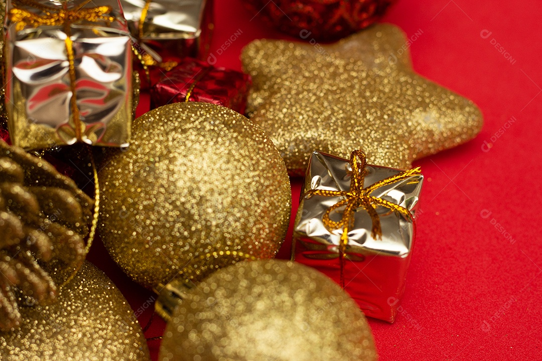 vários enfeites de natal dourados em fundo vermelho