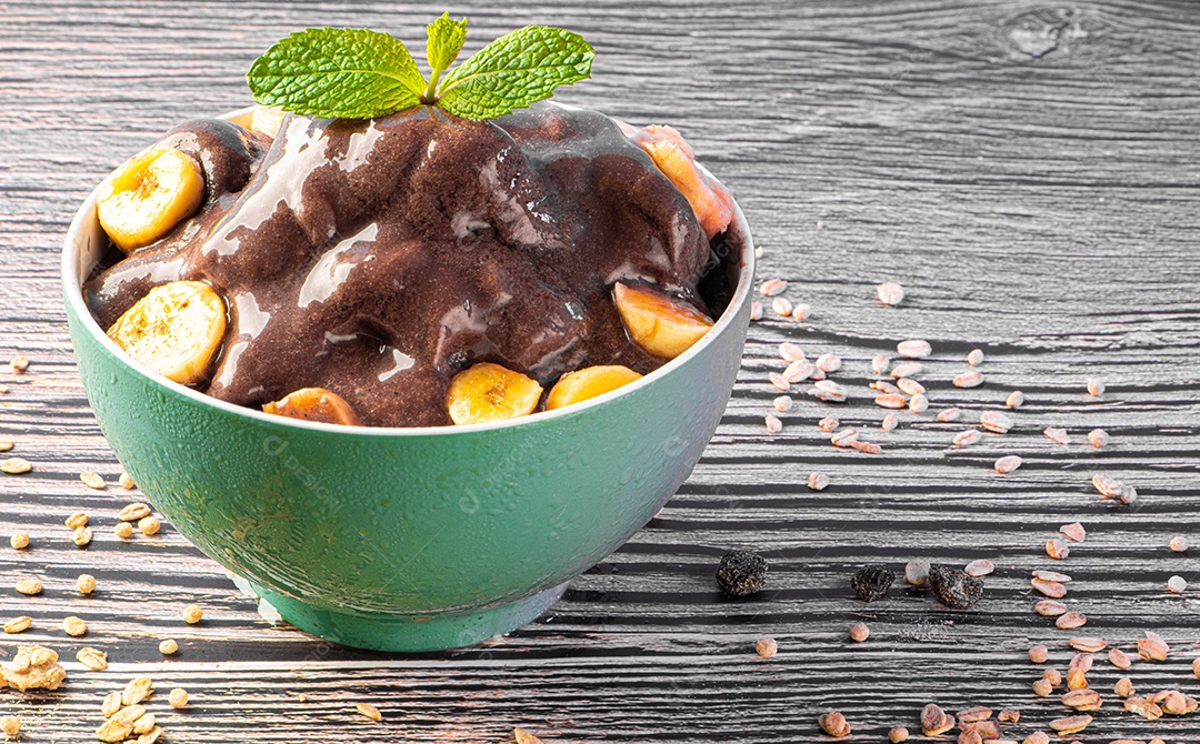 Tigela de sorvete de açaí congelado brasileiro. com frutas em fundo de madeira.